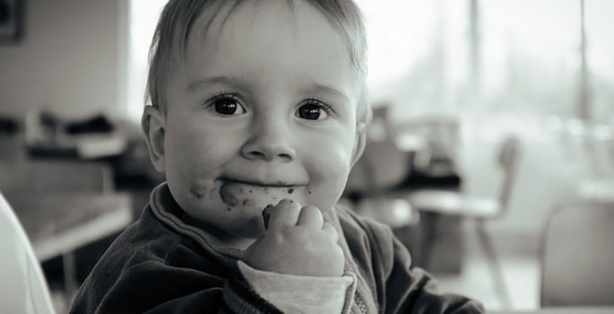 Barn som äter jordnötter. Ett livsmedel som många barn blir allergiska mot när de är små.